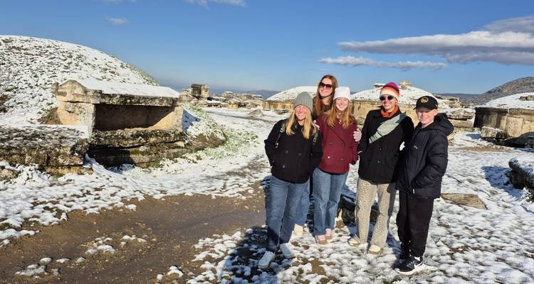 Groupe de personnes posant dans un paysage enneigé avec des ruines antiques.