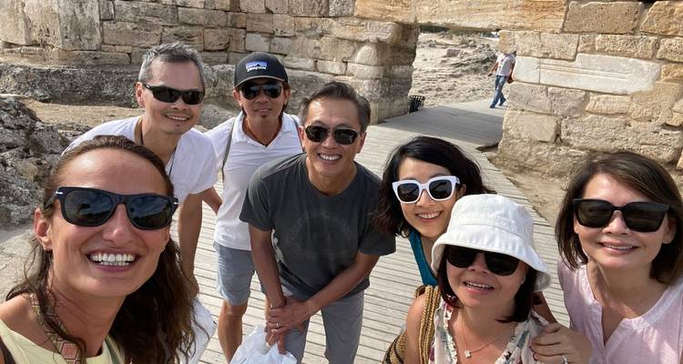 Selfie de groupe devant des ruines antiques avec chemin en bois.