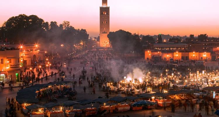 Jemaa el-Fnaa Platz in Marrakesch, Marokko, bei Sonnenuntergang mit geschäftigem Treiben und Lichtern.