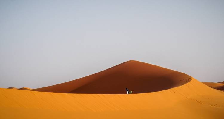 Eine Person, die auf einer Sanddüne in der Sahara-Wüste bei Merzouga, Marokko steht.