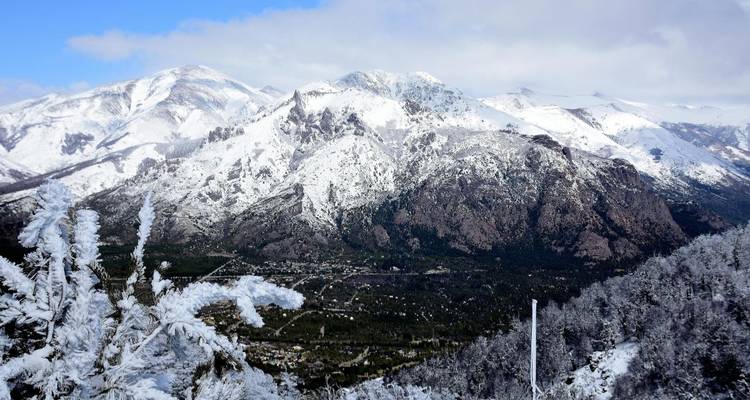 Paisaje montañoso cubierto de nieve con un bosque abajo.