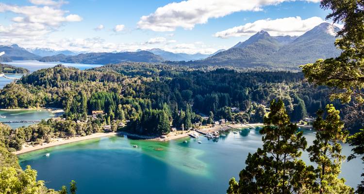 Vue panoramique d'une baie boisée avec des montagnes et une eau claire.