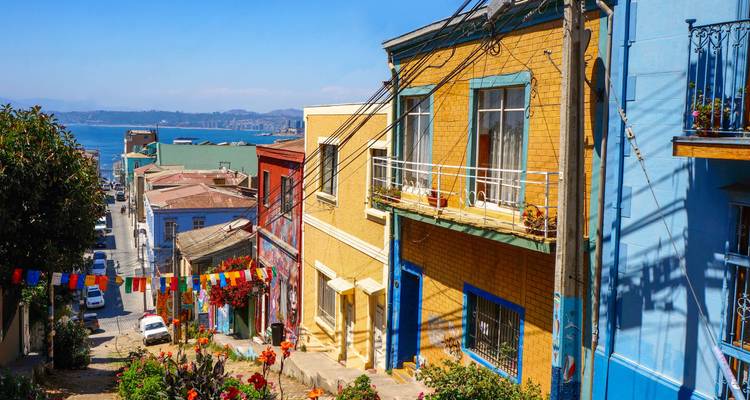 Maisons colorées sur une colline surplombant la mer avec des guirlandes lumineuses suspendues.