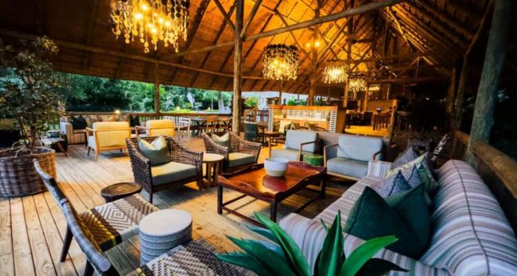 Stilvolle Freiluft-Lodge-Lounge mit Holzbalken, warmer Beleuchtung und bequemen Sitzgelegenheiten.