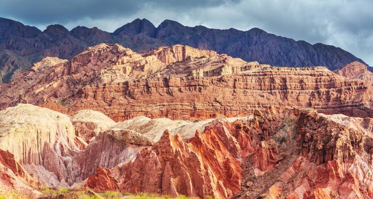 Paysage montagneux accidenté aux teintes riches sous des nuages dramatiques.