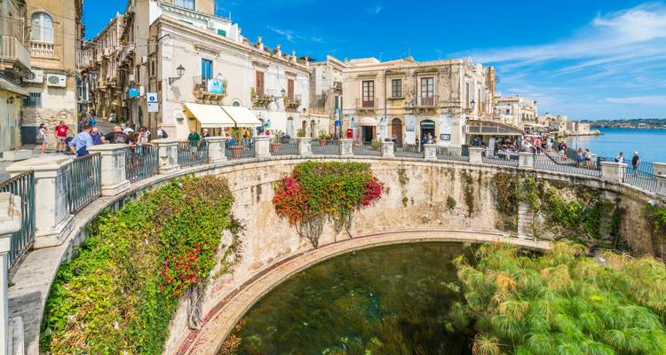 Manantial circular de agua dulce Fonte Aretusa rodeado de flores junto al paseo marítimo de Siracusa