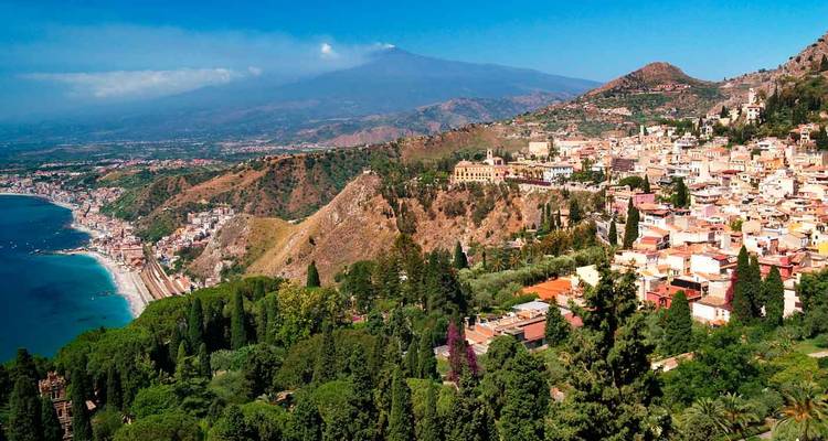 Vue panoramique depuis Taormina sur les collines luxuriantes, les plages de sable et le mont Etna au loin.