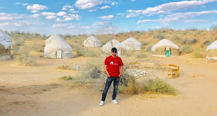 Un homme debout devant des yourtes dans un paysage désertique