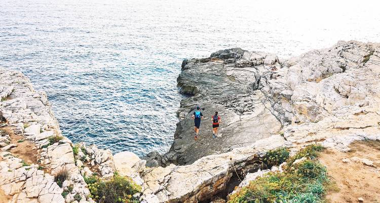 Deux personnes courant sur un terrain côtier rocheux