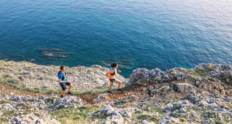 Deux coureurs sur un sentier de falaise avec vue sur l'océan