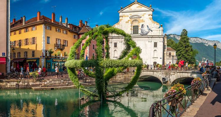Charmante scène de canal bordée de bâtiments colorés et d'un pont fleuri dans une ville de montagne.