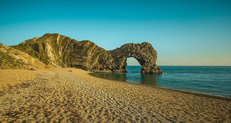 Durdle Door avec plage de sable et ciel dégagé.