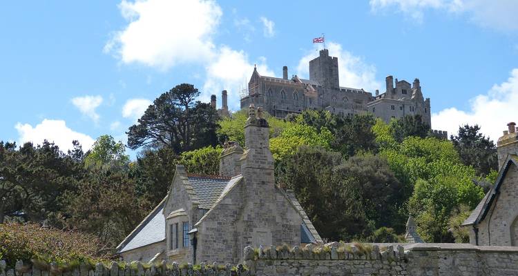 Château sur une colline avec un drapeau, entouré d'arbres.