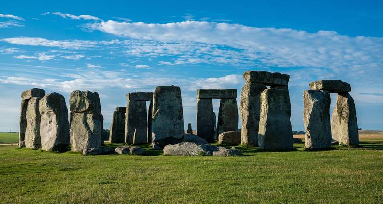 Stonehenge sous un ciel bleu vif avec des nuages épars.