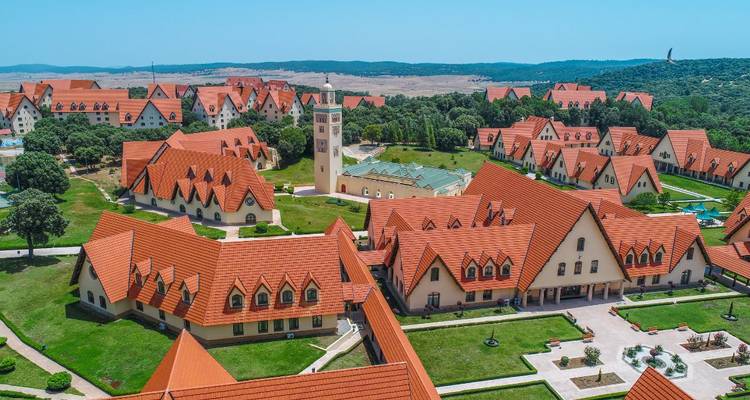 Großer Gebäudekomplex mit roten Dächern und einem Uhrenturm.
