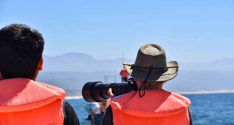 Dos personas con chalecos salvavidas mirando hacia el agua.