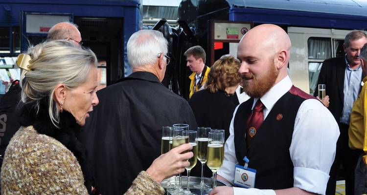 Des gens savourant une boisson et interagissant debout à côté d'un train.