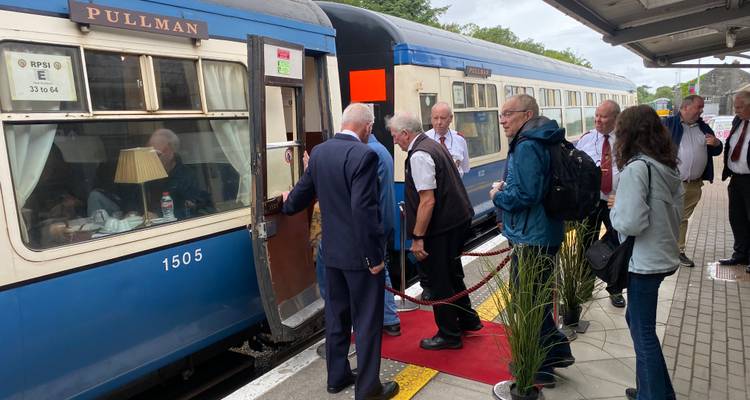 Des gens montant à bord d'un train Pullman bleu et blanc.