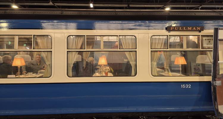 Vue intérieure d'un train Pullman avec des personnes visibles à travers la fenêtre.