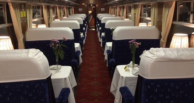 Intérieur d'une voiture de train avec des tables et des chaises installées pour les repas.
