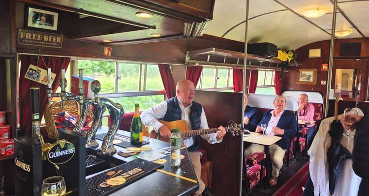 Des gens qui profitent de musique live avec un guitariste à l'intérieur d'un train.