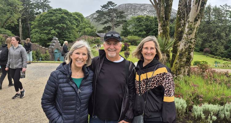 Groupe de personnes posant en extérieur dans un jardin avec des arbres et une montagne en arrière-plan.