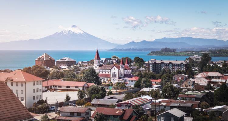 Paysage urbain avec un grand volcan enneigé en arrière-plan.