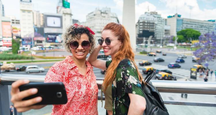Deux personnes prenant un selfie avec le paysage urbain en arrière-plan.