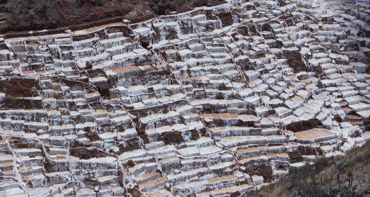 Vue de haut de centaines de bassins de sel en terrasses à Maras formant des motifs blancs abstraits.