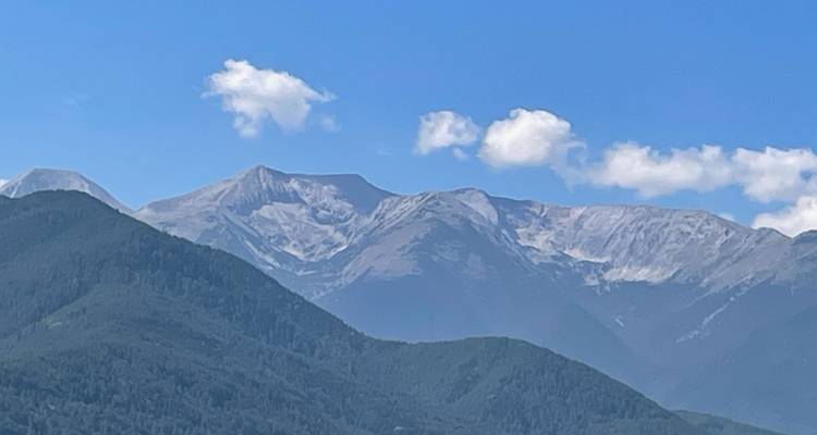 Chaîne de montagnes aux sommets enneigés sous un ciel bleu.