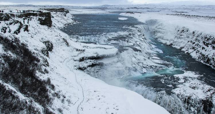 Powerful Gullfoss waterfall crashes through a snowy canyon under a winter sky.
