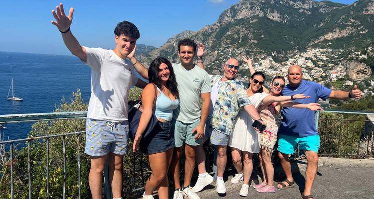 Grupo de personas posando con un pintoresco fondo costero.