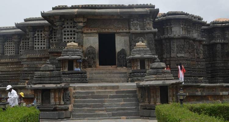 Templo de piedra tallada con escalones y vegetación.