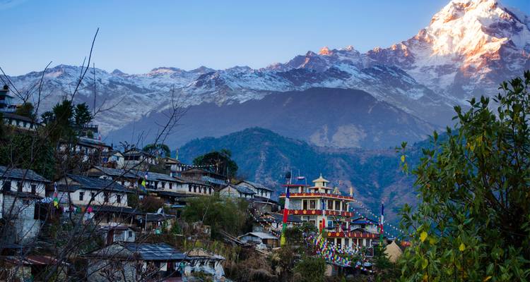 Zonovergoten dorp met besneeuwde bergen.