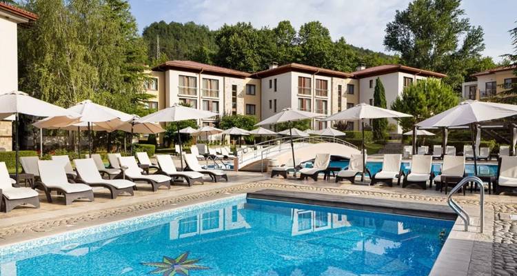 Complexe hôtelier avec une piscine entourée de transats et de parasols.