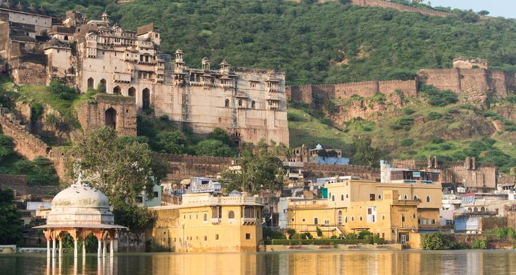 Stadtpalast von Bundi vor einem bewaldeten Hang, der sich im Wasser spiegelt.
