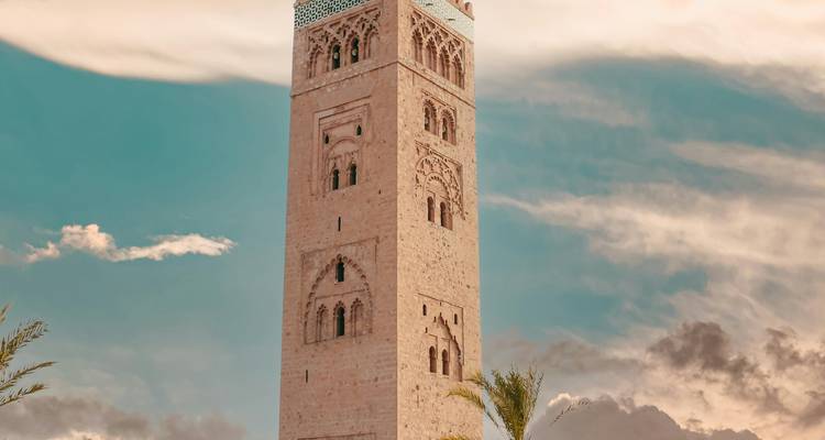 Ein hoher Minarettturm vor einem leuchtend blauen Himmel in einer Stadtlandschaft.