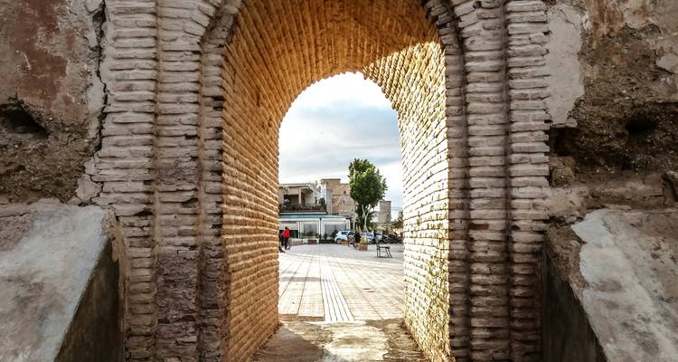 Vista a través de un arco histórico de ladrillo que conduce a un patio abierto.