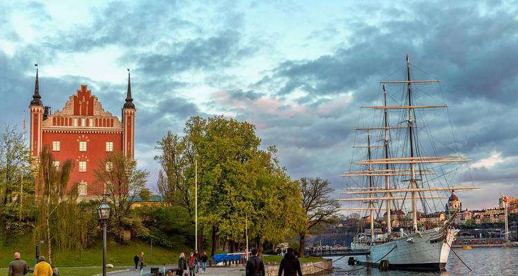 Vue panoramique d'un navire et de personnes se promenant le long d'un front de mer dans une ville.