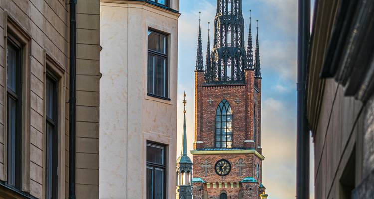 Tour d'église en brique vue entre les bâtiments de la ville.