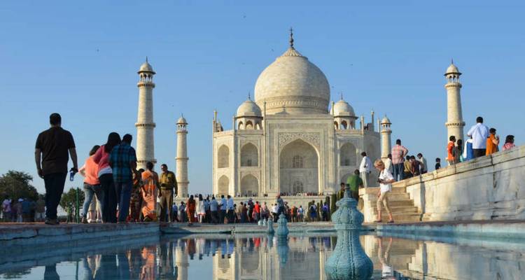 Visitantes en el Taj Mahal con una piscina reflectante en primer plano.