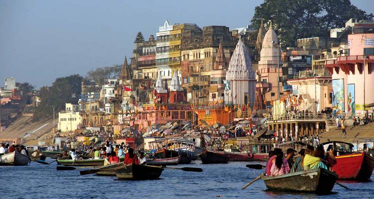 Barcas en el río Ganges con edificios coloridos de Varanasi al fondo.