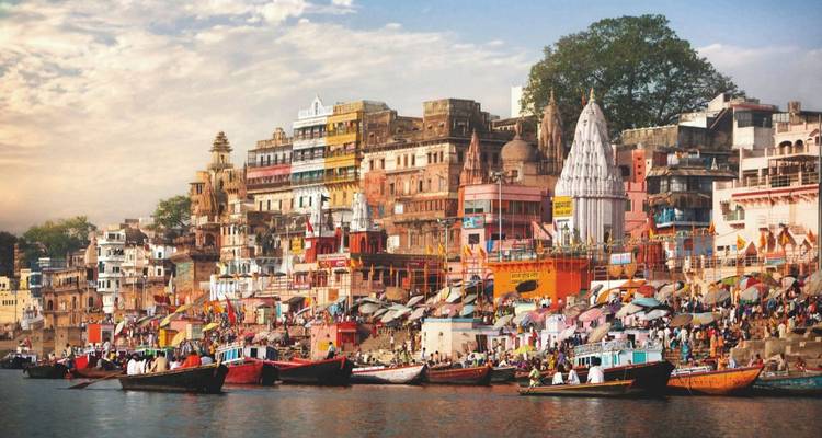 Vista colorida de los ghats de la ribera en Varanasi con botes y edificios.
