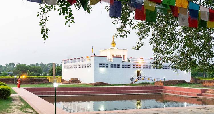 Complejo de templos con banderas de oración y una piscina reflectante.