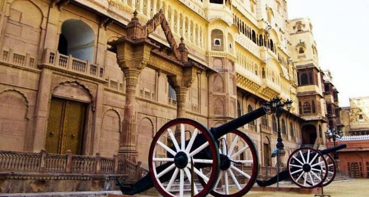 Fuerte histórico con cañones frente a un edificio arquitectónico ornamentado.