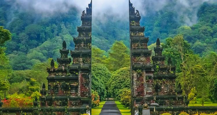 Icónica entrada de puerta dividida de Handara Gate enmarcada por un exuberante bosque tropical y montañas brumosas en Bali.