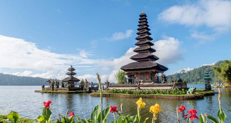 Complejo del templo Ulun Danu Bratan flotando en las aguas tranquilas del lago con flores coloridas en primer plano, Bali.