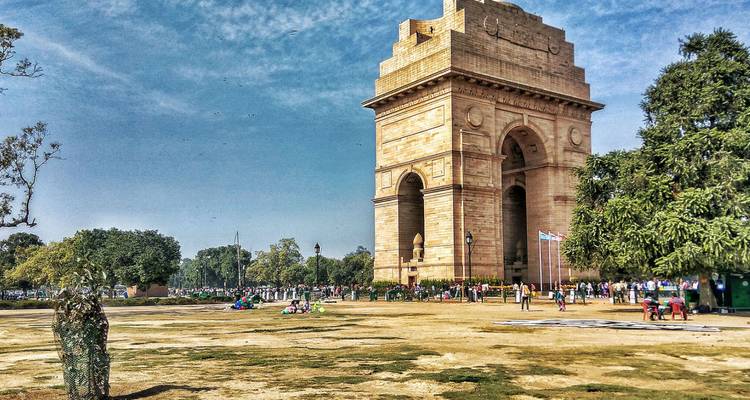 Porte de l'Inde avec des gens rassemblés autour, située dans un paysage de parc.