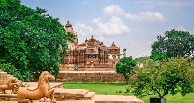 Temple ancien aux sculptures complexes entouré de verdure.
