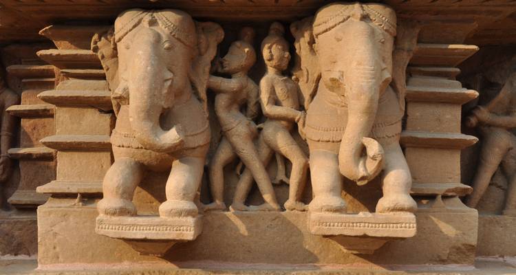 Gros plan de sculptures anciennes en pierre représentant des personnages et des éléphants.